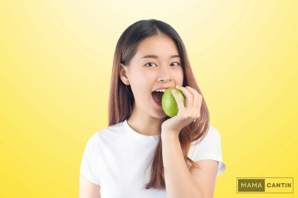 Wanita sedang memakan buah apel