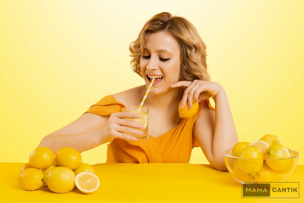 Wanita sedang minum minuman dari lemon